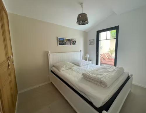 une chambre blanche avec un lit avec une fenêtre dans l'établissement Villa Les Lopins, à Arcachon