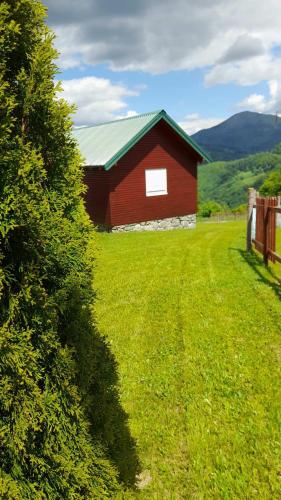 a red barn with a green roof in a field at Ethno village & resort Ćorić in Mojkovac