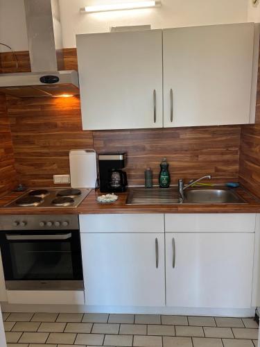 a kitchen with white cabinets and a sink and a stove at Ferienwohnungen im Taunusblick in Lahnstein
