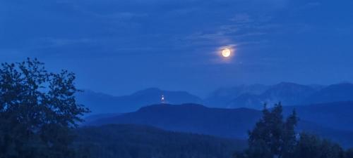 a night view of a lighthouse on a hill with the moon at ZAUBERBERG Apartements in Schwarzendorf