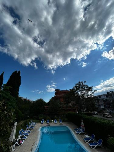 a swimming pool with chaise lounges and lawn chairs at Family Hotel Magnolia, Sunny Beach in Sunny Beach