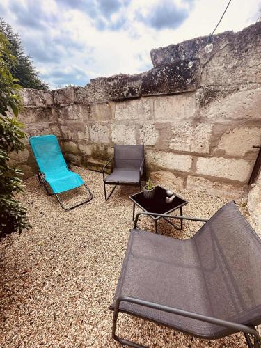 two chairs and a table in front of a stone wall at gîte Cosy Green 2 in Chevincourt