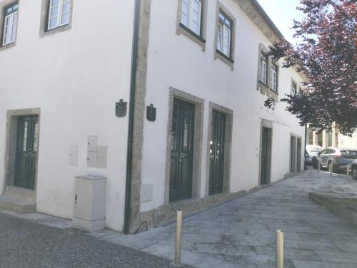 a white building with a pole next to a street at Casa do Forno in Ponte da Barca