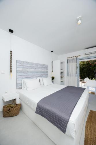 a white bedroom with a large bed and a window at Flisvos beach studios in Naxos Chora