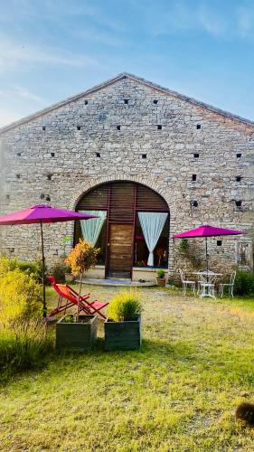 a brick building with tables and chairs and umbrellas at La bastide de Meilhouret in Larroque