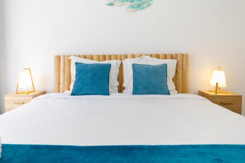 a bedroom with a large white bed with blue pillows at LA PERLE 2 P Terrasse Vue Mer 1min Plage Clim in Roquebrune-Cap-Martin