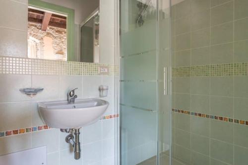 a bathroom with a sink and a glass shower at Madalen Guest House in Bosa