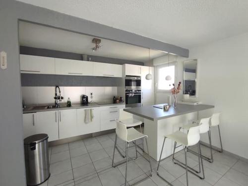 une cuisine avec des armoires blanches et une table et des chaises dans l'établissement Appartement cosy dans résidence avec piscine, à Saint-Raphaël