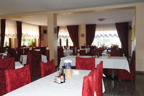 una sala da pranzo con tavoli bianchi e sedie rosse di Hotel San Remo a San Zeno di Montagna
