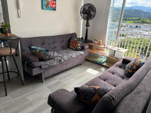 a living room with two couches and a large window at Mi hogar en Ibagué in Ibagué