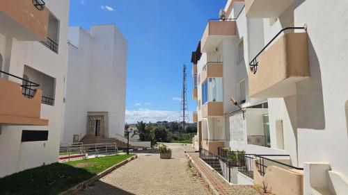 an alley between two white buildings with a blue sky at Apparemment Achakar in Tangier