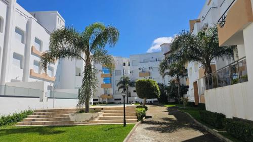a courtyard of a building with palm trees and stairs at Apparemment Achakar in Tangier