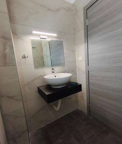 a bathroom with a sink and a shower with a mirror at Beachway luxury studio C in Nea Peramos