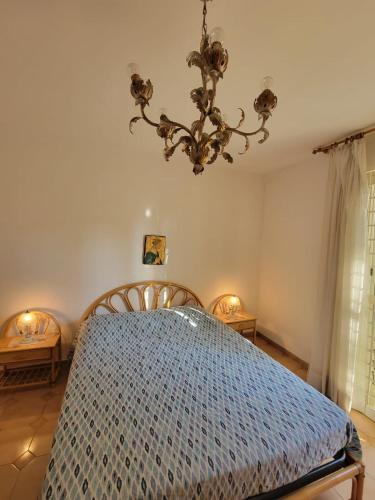 a bedroom with a blue bed with a chandelier at Etna view Villa Letizia a Taormina in Taormina