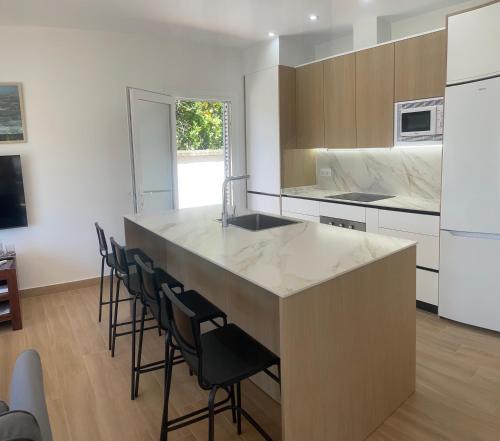 a kitchen with a large island with black chairs at Sunset Palm in El Puerto de Santa María