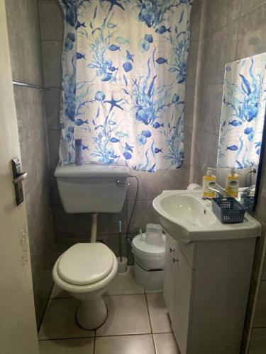a blue and white bathroom with a toilet and a sink at Bennyz Guest House in Pretoria