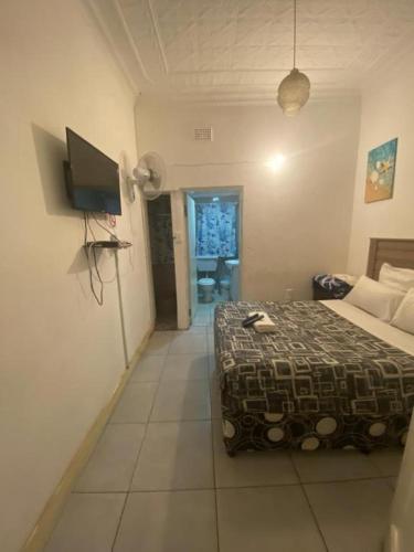 a bedroom with a bed and a flat screen tv at Bennyz Guest House in Pretoria