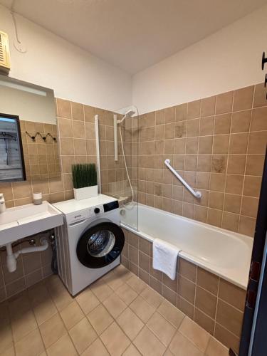 a bathroom with a washing machine next to a bath tub at Apartment Theresa in Bad Goisern