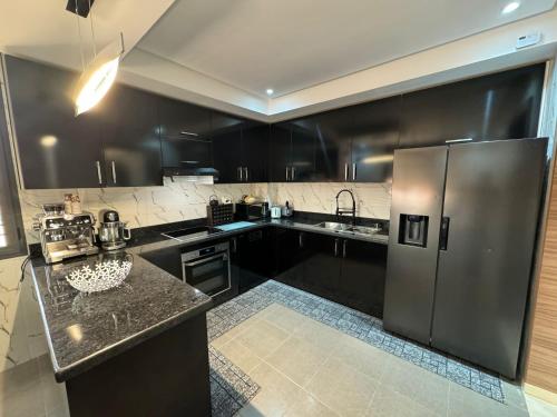 a kitchen with black cabinets and a stainless steel refrigerator at Maison Privée avec Sauna Marrakech in Chouiter