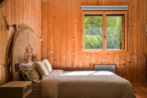 une chambre avec un grand lit et une fenêtre dans l'établissement Villa éco-lodge sur pilotis - Piscine, Vélo, Plancha - entre Bayonne et Hossegor, à Saint-Laurent-de-Gosse
