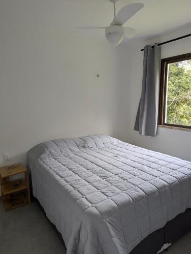 a white bed in a bedroom with a window at Guaramiranga - Apto próximo ao centro - Park Serra Bella in Guaramiranga