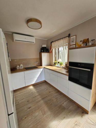 a kitchen with white cabinets and a black appliance at Dom całoroczny Tomek in Kopalino