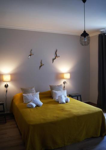 a bedroom with a yellow bed with birds on the wall at O Forte Guest House in Peniche