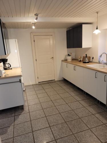 a kitchen with white cabinets and a white door at Lejbølle Gamle Bageri in Tranekær