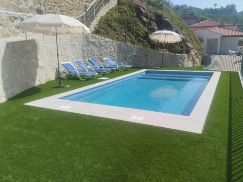 a swimming pool with two umbrellas and some grass at Casa da vinha in Anreade