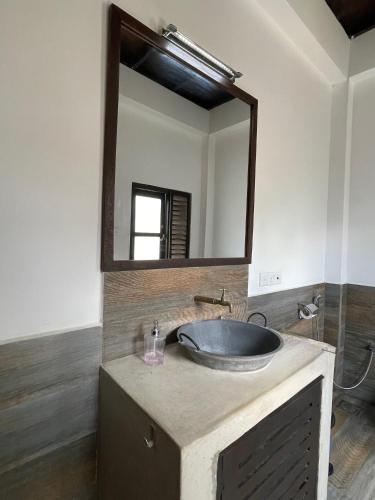 a bathroom with a sink with a large mirror at Downwinder Lagoon Lodge in Kalpitiya