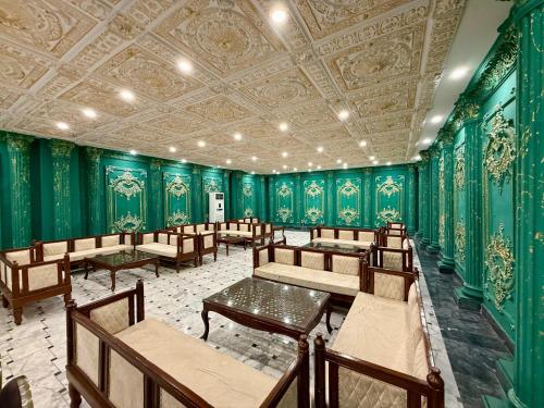 ein Raum mit grünen Wänden und Holztischen und -stühlen in der Unterkunft Marina Suites Lahore in Lahore