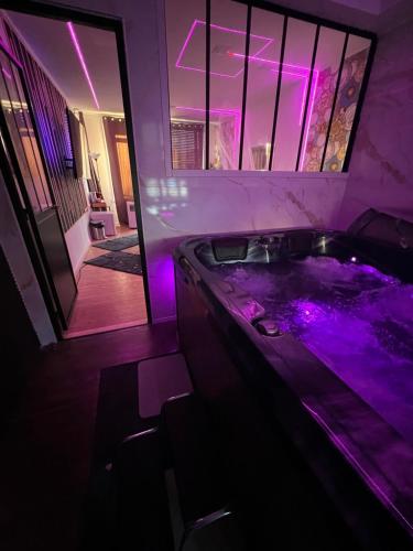 - une baignoire avec éclairage violet dans la chambre dans l'établissement Rigate spa, à Lens