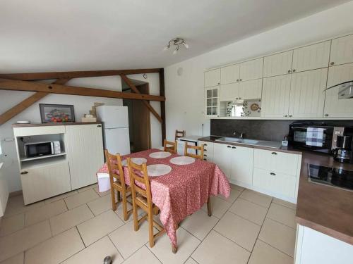 une cuisine avec une table et des chaises et une cuisine avec des armoires blanches dans l'établissement Maison plein pied Trosly-Loire, à Trosly-Loire