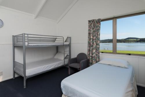 Waitangi Holiday Park في بيهْيا: غرفة نوم مع سرير بطابقين ونافذة