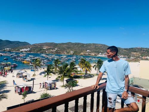a man standing on a balcony looking at a beach at Vista mar 1 in Arraial do Cabo