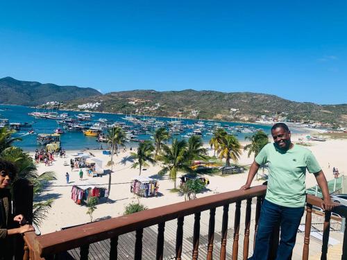a man standing on a balcony overlooking a beach at Vista mar 1 in Arraial do Cabo