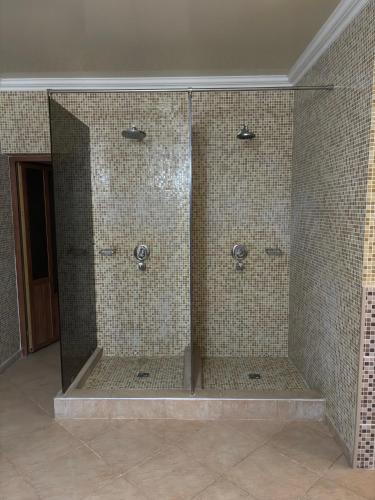 a bathroom with three shower stalls with tiled walls at Raiax in Hînceşti