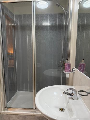 a bathroom with a shower and a white sink at 4 Sisters Inn in Theydon Bois