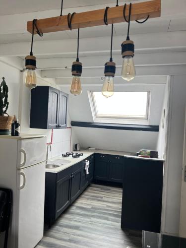 une cuisine avec des armoires noires, une fenêtre et des lumières dans l'établissement WingFlat Appartement Entier Centre Ville Proche Naval Cité de la mer Quartier Calme, à Cherbourg en Cotentin