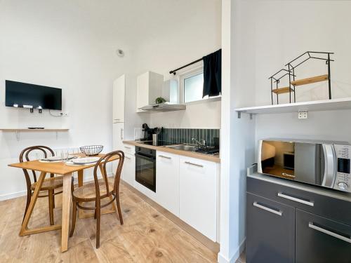 une cuisine avec une table et des chaises et un micro-ondes dans l'établissement La Belle Étoile - Calme - Plages & Cœur de St Malo, à Saint-Malo