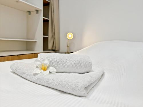 - une serviette blanche avec une fleur sur le lit dans l'établissement La Belle Étoile - Calme - Plages & Cœur de St Malo, à Saint-Malo