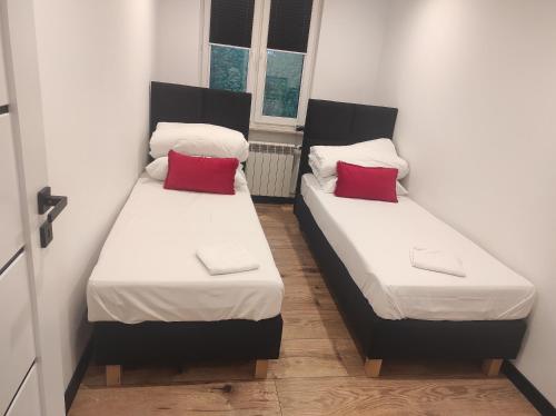 - 2 lits dans une petite chambre avec des oreillers rouges dans l'établissement BlackandWhite, à Sandomierz