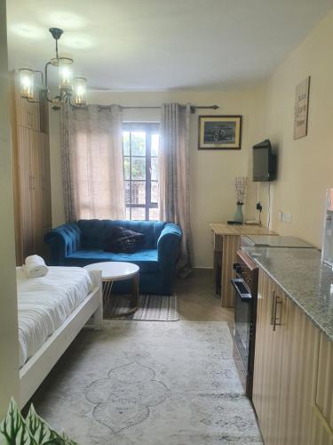 a living room with a blue couch and a kitchen at Regional Homes Ke 1004 in Nairobi