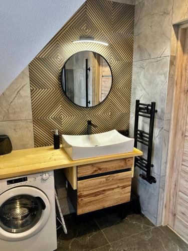 a bathroom with a sink and a washing machine at RatuApartament in Ratułów