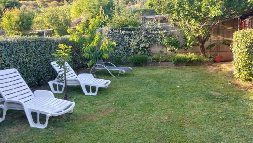 three white chairs sitting on the grass in a yard at Apartment Pirun in Baška