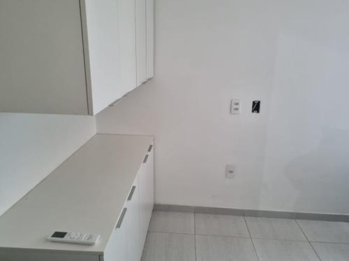 a room with white walls and a white bench with a remote control at Flat Enseada dos Corais in Cabo de Santo Agostinho