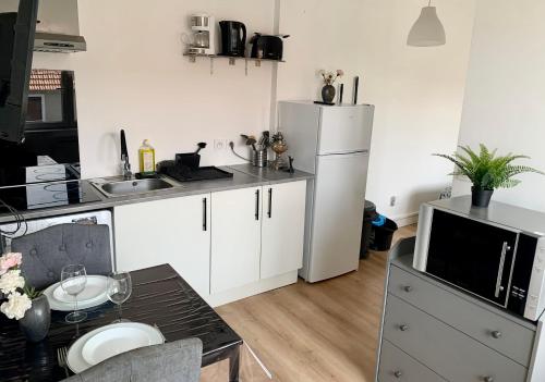 une cuisine avec des armoires blanches et un réfrigérateur blanc dans l'établissement Le Ptit Maisy, à Grandcamp-Maisy