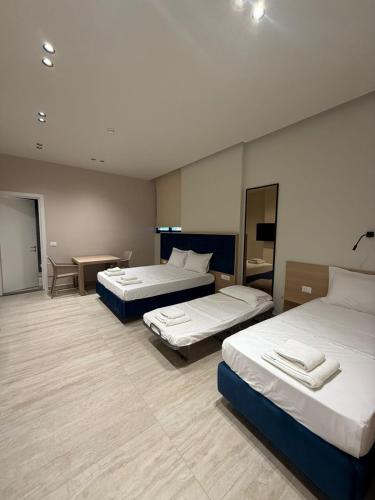 a hotel room with three beds and a table at ReiVal Hotel Marina Vlore in Vlorë