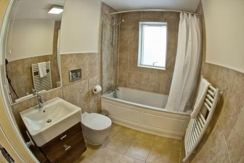a bathroom with a tub and a toilet and a sink at Pottergate Apartments 3 bedroom 2 bathroom Central Luxury Apartment in Norwich