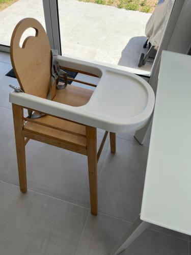 a wooden chair sitting in front of a window at Sables des Dunes, jolie maison neuve tout confort, vacances famille ou entre amis, 500 m plage in Brétignolles-sur-Mer